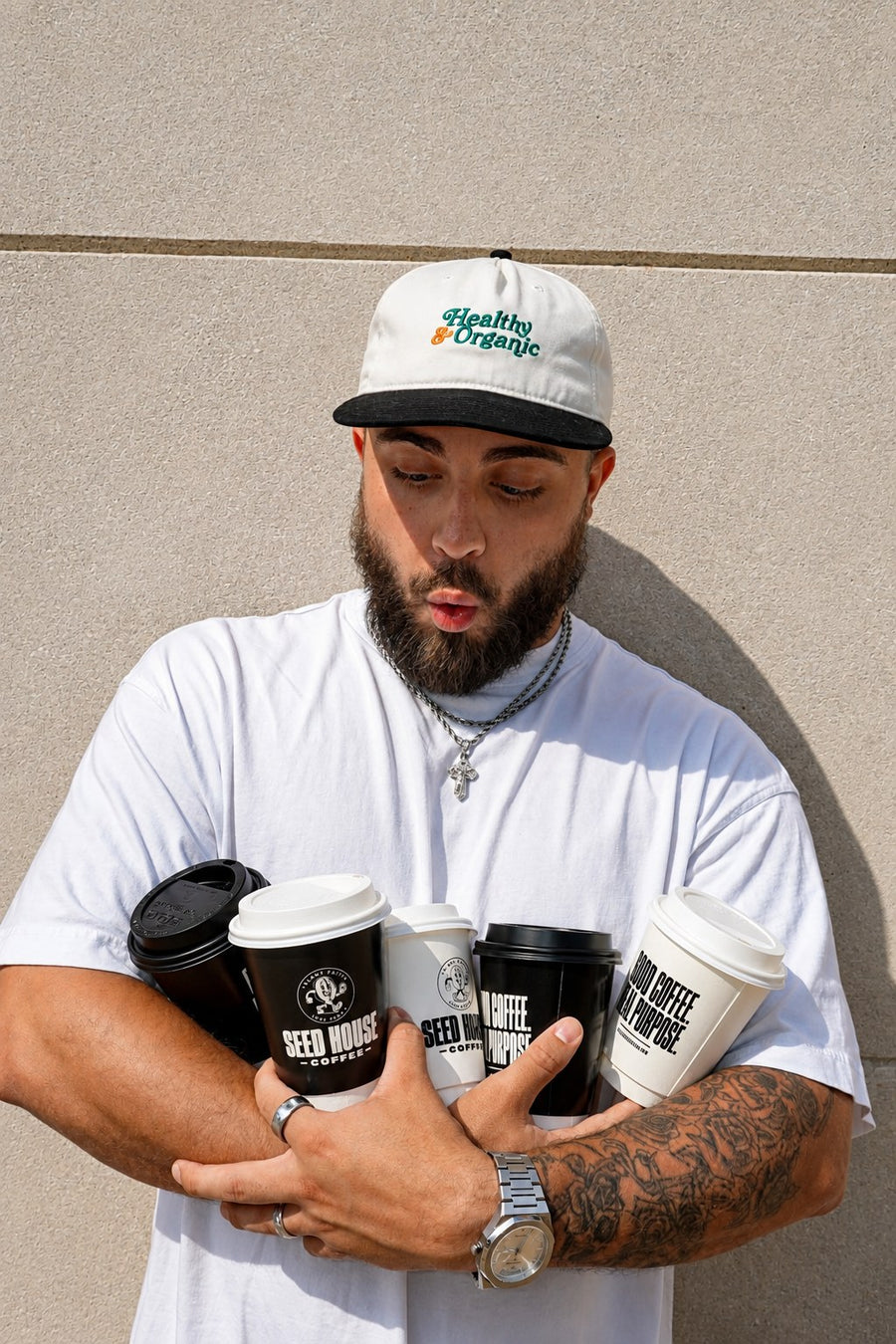 David Shiminsky, founder of Seed House Coffee, both arms full of Seed House cups on a Lansing sidewalk